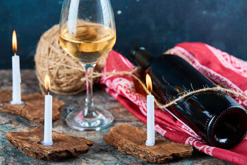 A glass of white wine and bottle with burning candles, close up