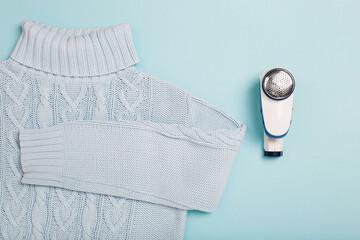 Lint Removerand sweater on blue background. Anti-pilling razor. Device for shaving clothes....