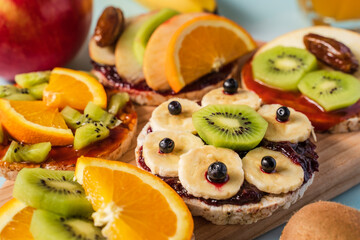 Crispy puffed rice cakes on table with fresh fruit kiwi banana apple blueberries and orange on the table - close up view on healthy organic vegetarian or vegan breakfast gluten free