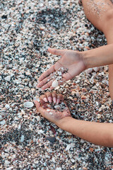 woman's hands playing with seashells on the beach