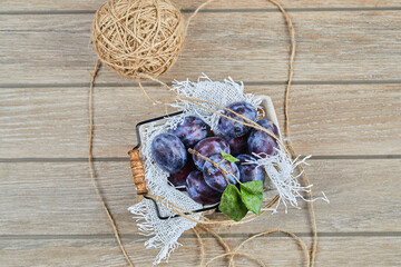 Garden plums in a basket on a wooden table