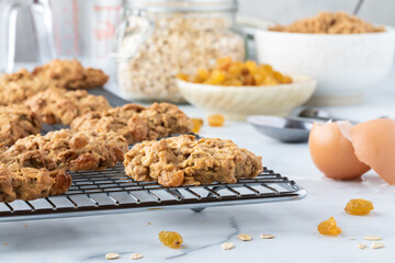 Warm oatmeal raisin cookies cooling on a metal cooling rack with recipe ingredients to the side.