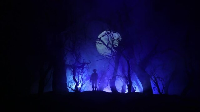 bloodthirsty zombies attacking concept. Silhouette of scary zombie walking in the dead forest at night. Creative table decorations. Selective focus