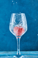 A glass of juice with strawberry inside on blue background