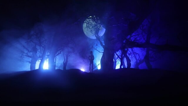 bloodthirsty zombies attacking concept. Silhouette of scary zombie walking in the dead forest at night. Creative table decorations. Selective focus