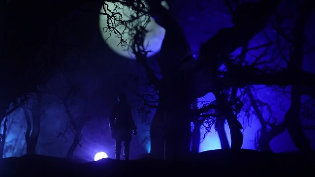 bloodthirsty zombies attacking concept. Silhouette of scary zombie walking in the dead forest at night. Creative table decorations. Selective focus
