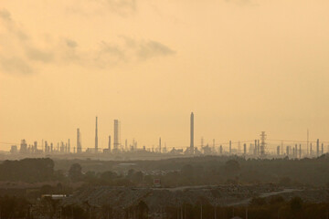 Fototapeta na wymiar Industrial city skyline of factory towers against an orange sunset sky