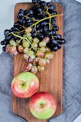 Red green apples and grape bunches on a wooden board