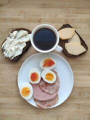 eggs, ham, cheese, bread and coffee for breakfast on the wood.