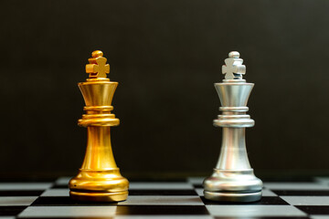 Gold king in chess game face with the another silver king on black background (Concept for company strategy, business victory or decision)