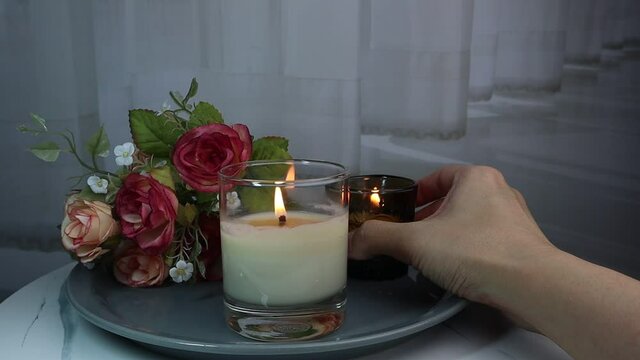 luxury aroma scented candles are put in the ceramic holder on the white marble table with bouquet of roses in bedroom background of curtain to creat romantic and relax ambient on valentine day