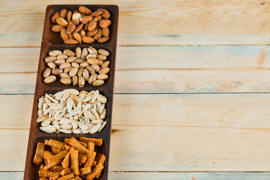 Crackers, pistachios and almonds on wooden platter