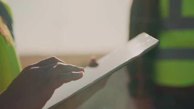 A woman uses a tablet as her coworker stands by