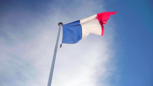 Looking up the French flag waving on its own in strong wind on a blue and cloudy sky