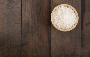 Fototapeta na wymiar Jasmine rice in wooden bowl on grunge wooden table background with copy space,top view