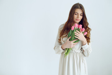 Beautiful woman with tulips. Spring bouquet in the hands of a young and happy girl. High quality photo.