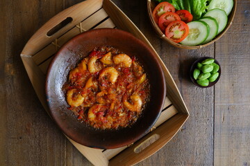 a plate of prawn cooked in sambal in an earhenware plate named gami udang is an Indonesian cuisine from Bontang, Borneo.