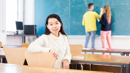 Portrait of female chinese student in auditorium, students writing on whiteboard