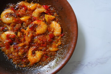 a plate of prawn cooked in sambal in an earhenware plate named gami udang is an Indonesian cuisine from Bontang, Borneo.
