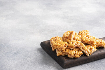 Peanuts in sugar glazed, oriental sweetness of brittle. Kozinaks are broken into pieces on a wooden Board, copy space.