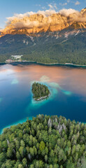 Aerial drone shot of Alpenglow with fog on Zugspitze by Eibsee lake in Germany