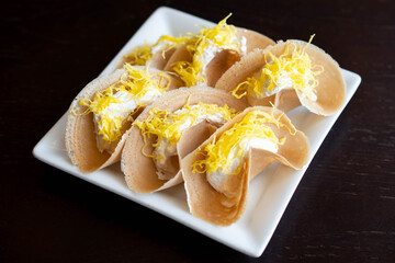 Close up of Thai crispy pancake (Khanom bueang) on white plate.