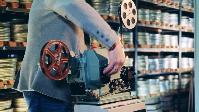 Archive worker is inserting film tape into the projector