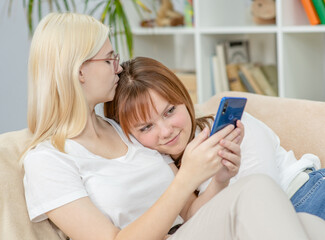 Happy lesbian couple embracing and using smartphone.  Lesbian couple concept