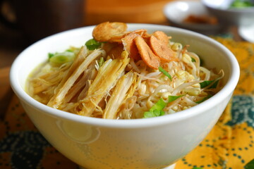 a bowl of Indonesian clear soup named soto Kudus, it contains of rice, vegetables and chicken meat