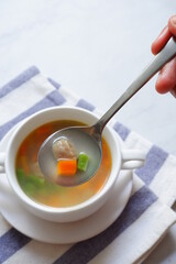 vegetable soup in a spoon from a bowl on a white background