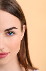 Beautiful young wearing rainbow contact lenses on color background