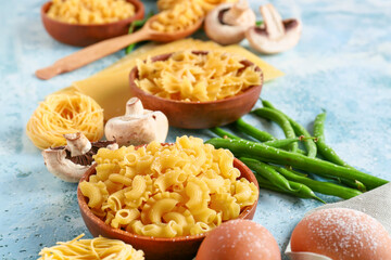 Assortment of dry pasta and products on color background