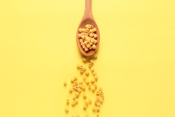 Spoon with dry pasta on color background