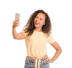 Young woman with mobile phone taking selfie on white background