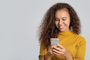 Young woman with mobile phone on light background