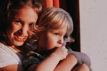 Close up portrait of siblings, sister and brother in sunset light. Shadows on the faces. Love, happines, family, childhood concept.