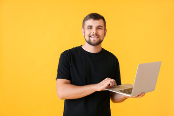 Young man with laptop on color background
