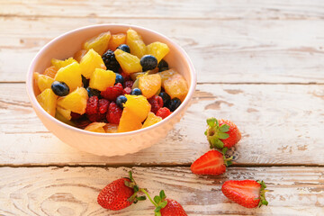 Bowl with fruit salad on wooden background