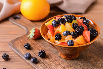 Bowl with fruit salad on wooden background