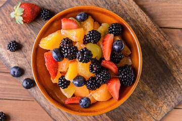 Bowl with fruit salad on wooden background
