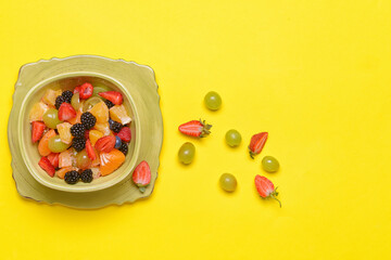Bowl with fruit salad on color background