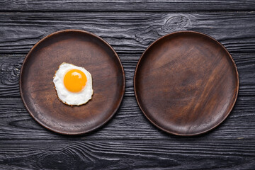 Plate with tasty fried egg on dark wooden background
