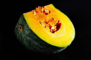 Bright cut pumpkin isolated on a black background, close-up. Beautiful vegetable background,...