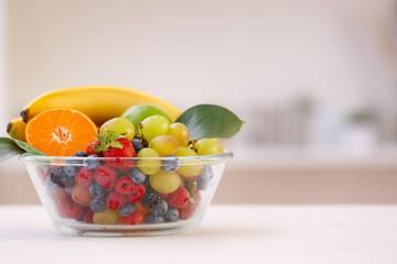 Bowl with different fruits and berries on table