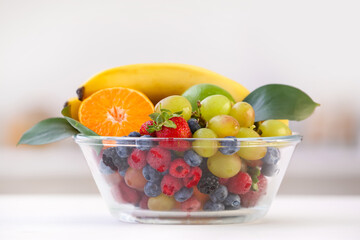 Bowl with different fruits and berries on table