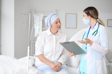 Doctor telling news to mature woman after chemotherapy in clinic