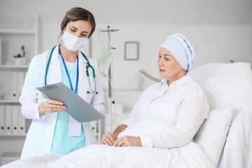 Doctor telling news to mature woman after chemotherapy in clinic