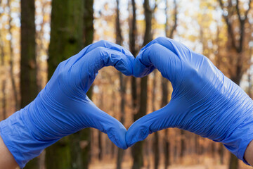 Hands in gloves folded in form of heart in forest