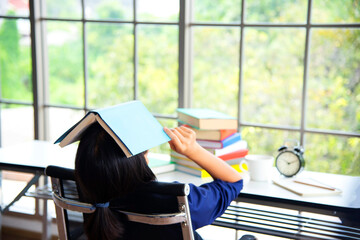 Obraz premium Tired Girlholding a book over his head.The concept of pre-school education. Education