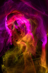 Portrait of young woman amid light painting , Over Black Background. Long exposure photo without photoshop, light drawing at long exposure